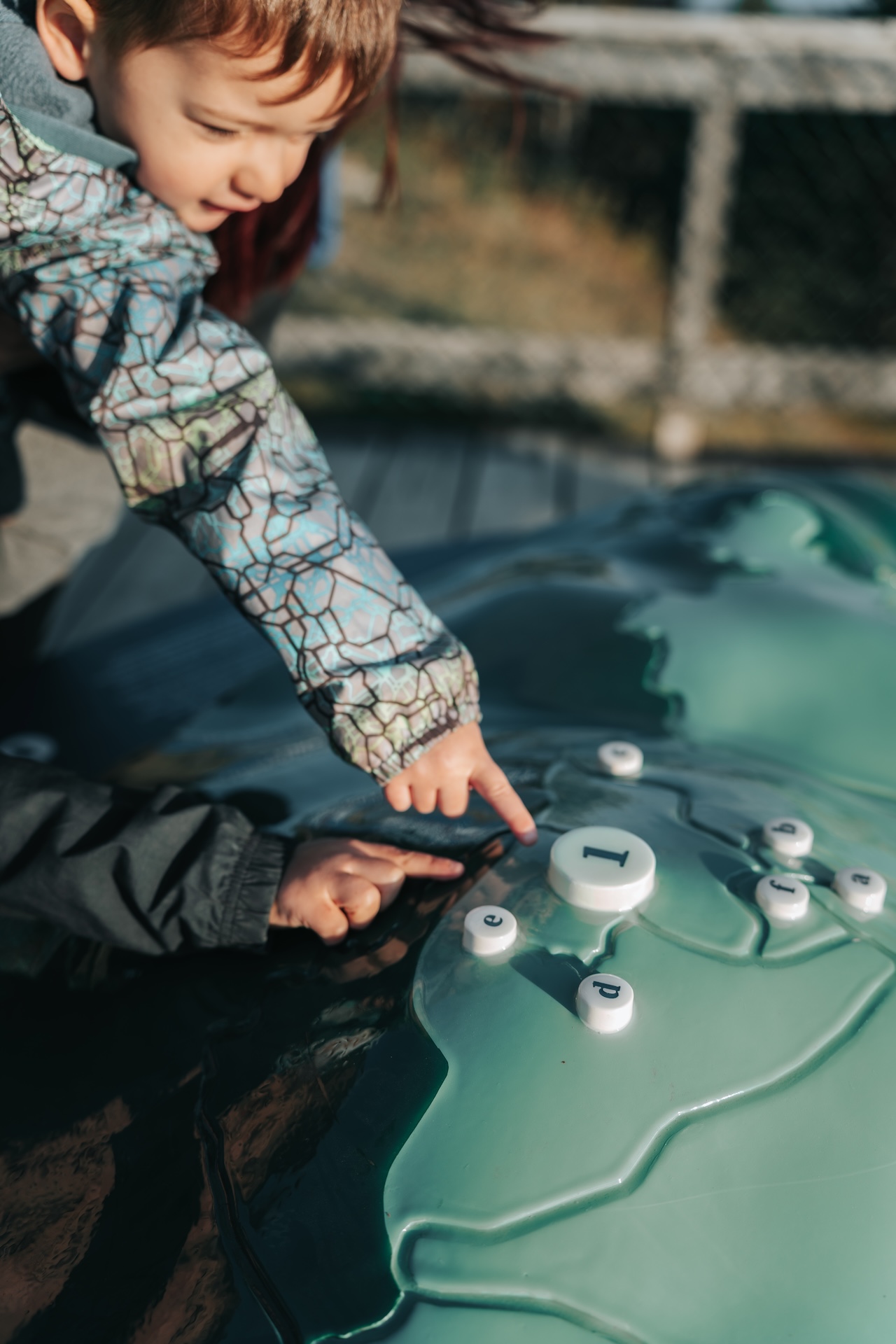 Enfant explore une installation interactive en forme de carte avec des boutons numérotés.