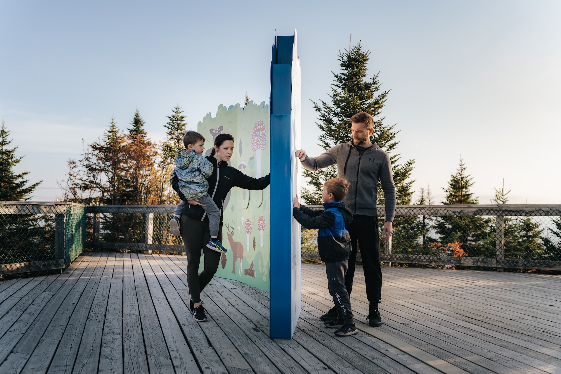 Famille interagissant avec une installation muséographique en extérieur, œuvre de Studio Overall.