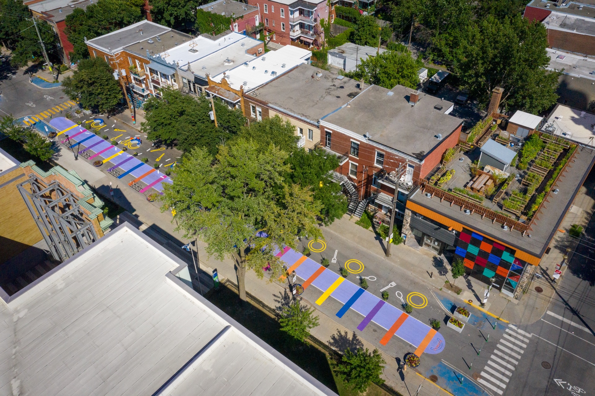 Vue aérienne d'une rue colorée avec installations artistiques et espaces verts urbains.