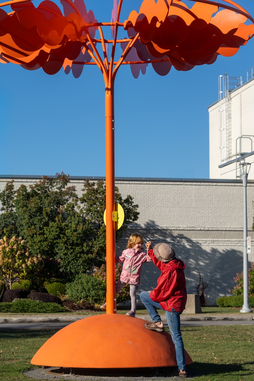Installation artistique orange avec enfants jouant autour, œuvre de Studio Overall.
