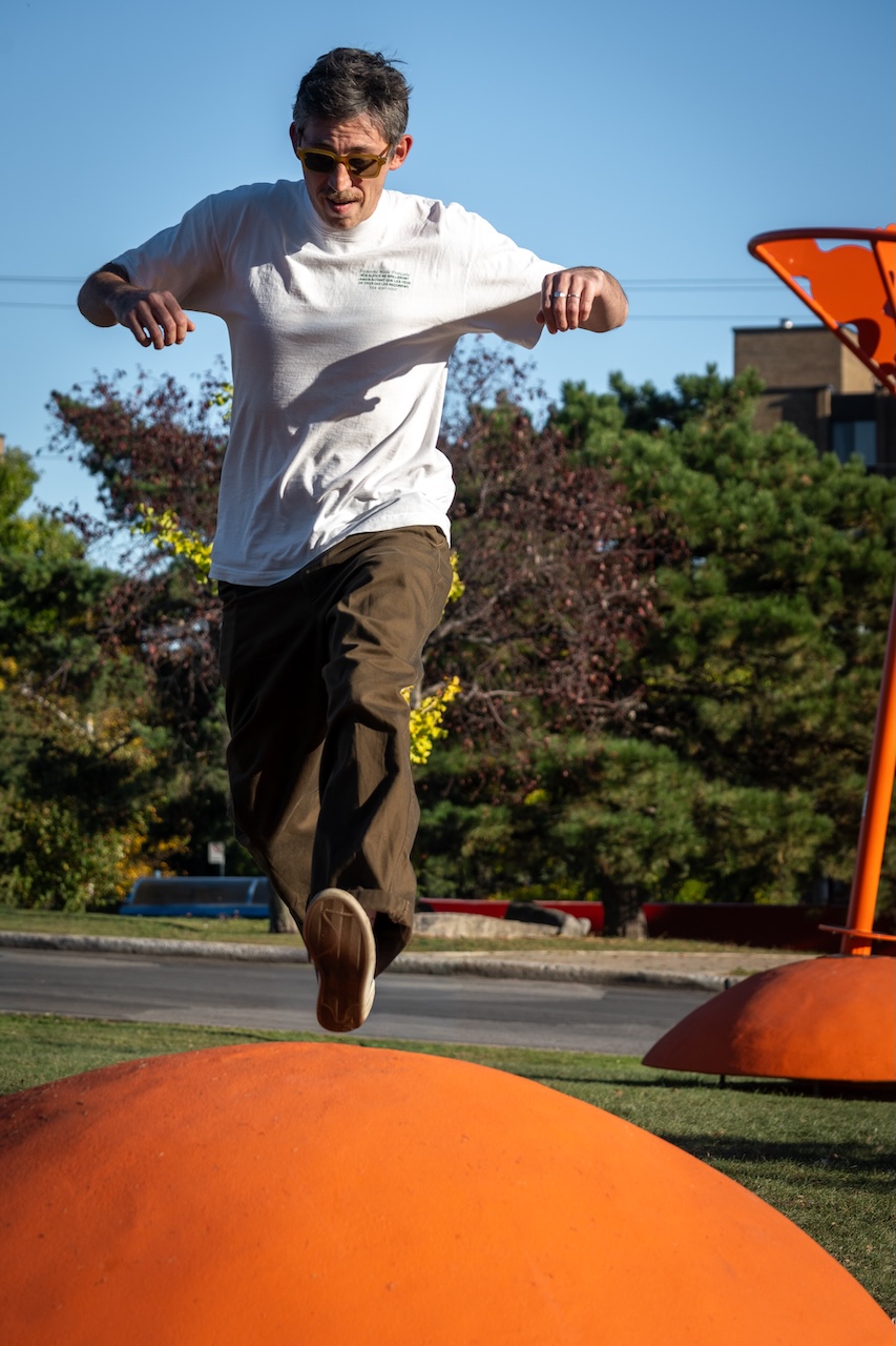 Homme sautant sur une installation orange en plein air, œuvre de Studio Overall.