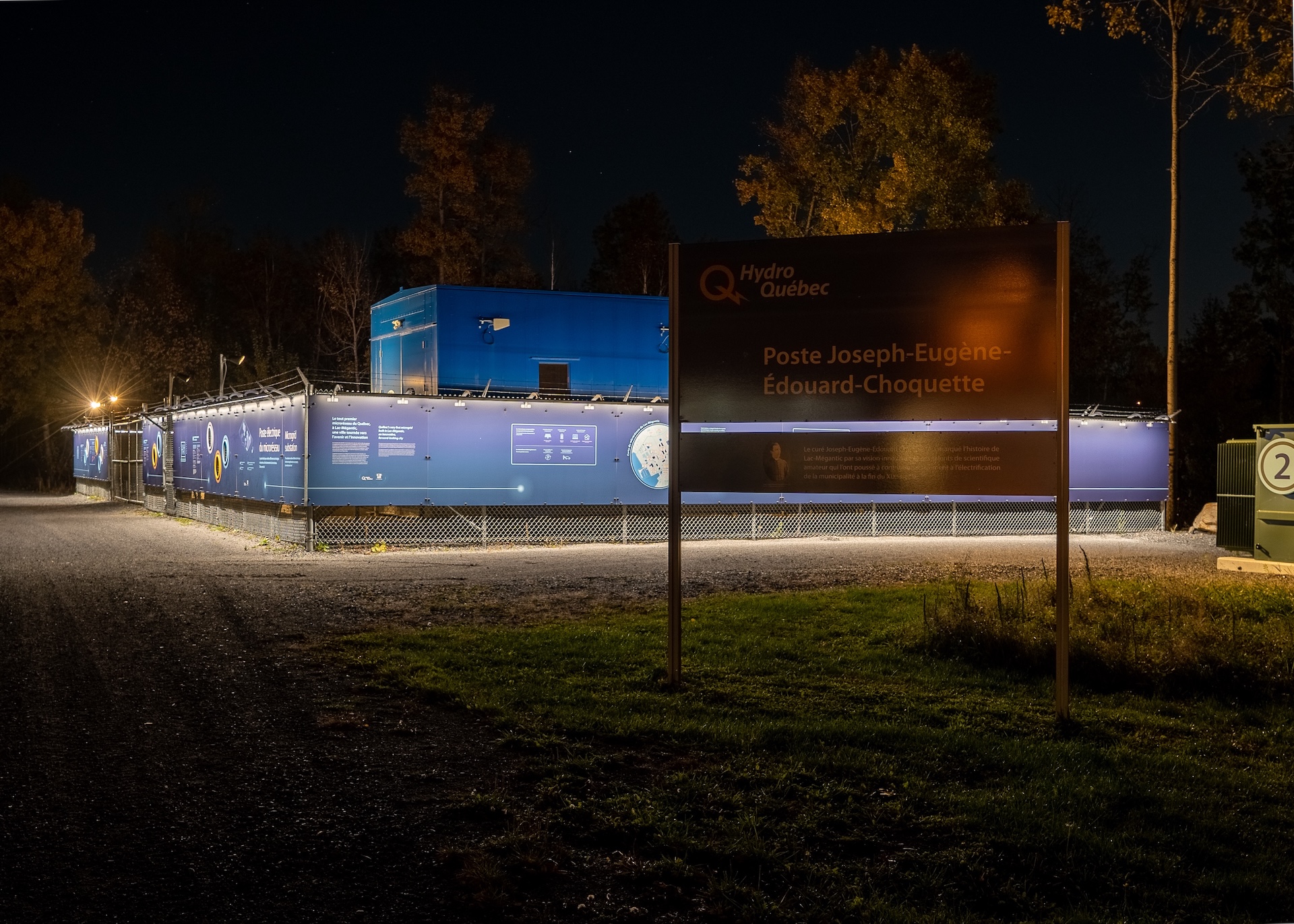Installation énergétique de Hydro Québec, avec panneau explicatif et clôture éclairée de nuit.
