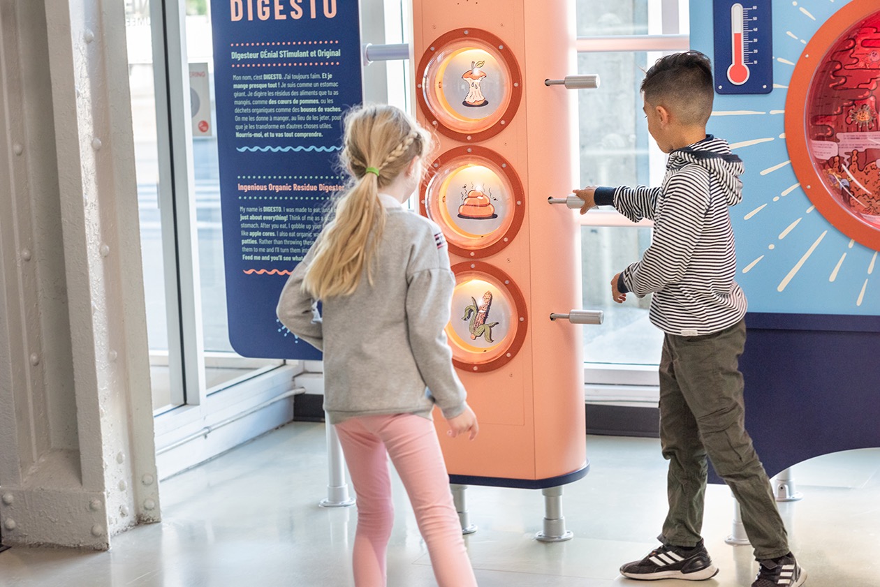 Enfants interagissant avec une installation éducative sur le système digestif dans un musée.