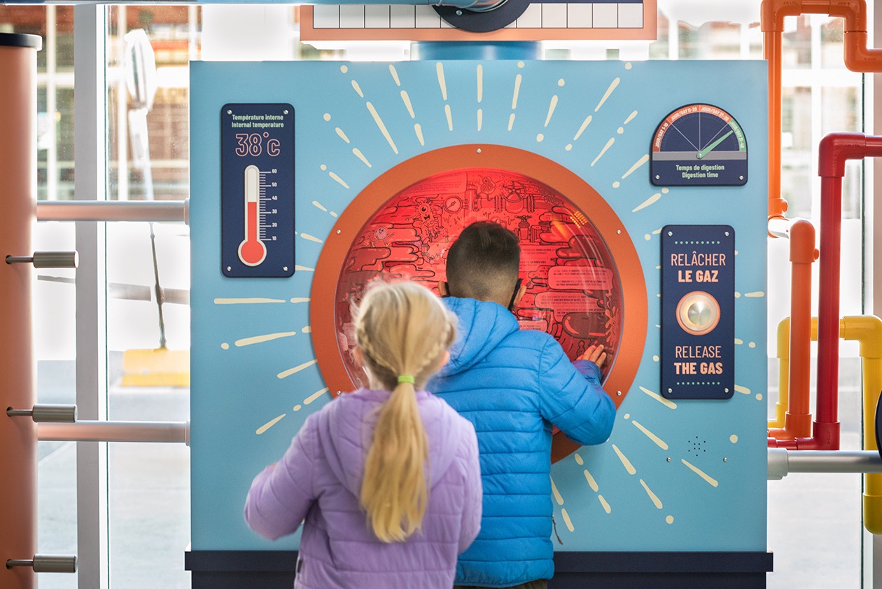 Deux enfants interagissent avec une installation éducative sur le système digestif.
