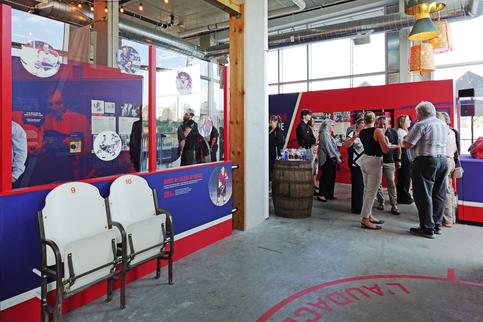 Exposition muséographique de Studio Overall avec visiteurs et sièges d'ancien stade.
