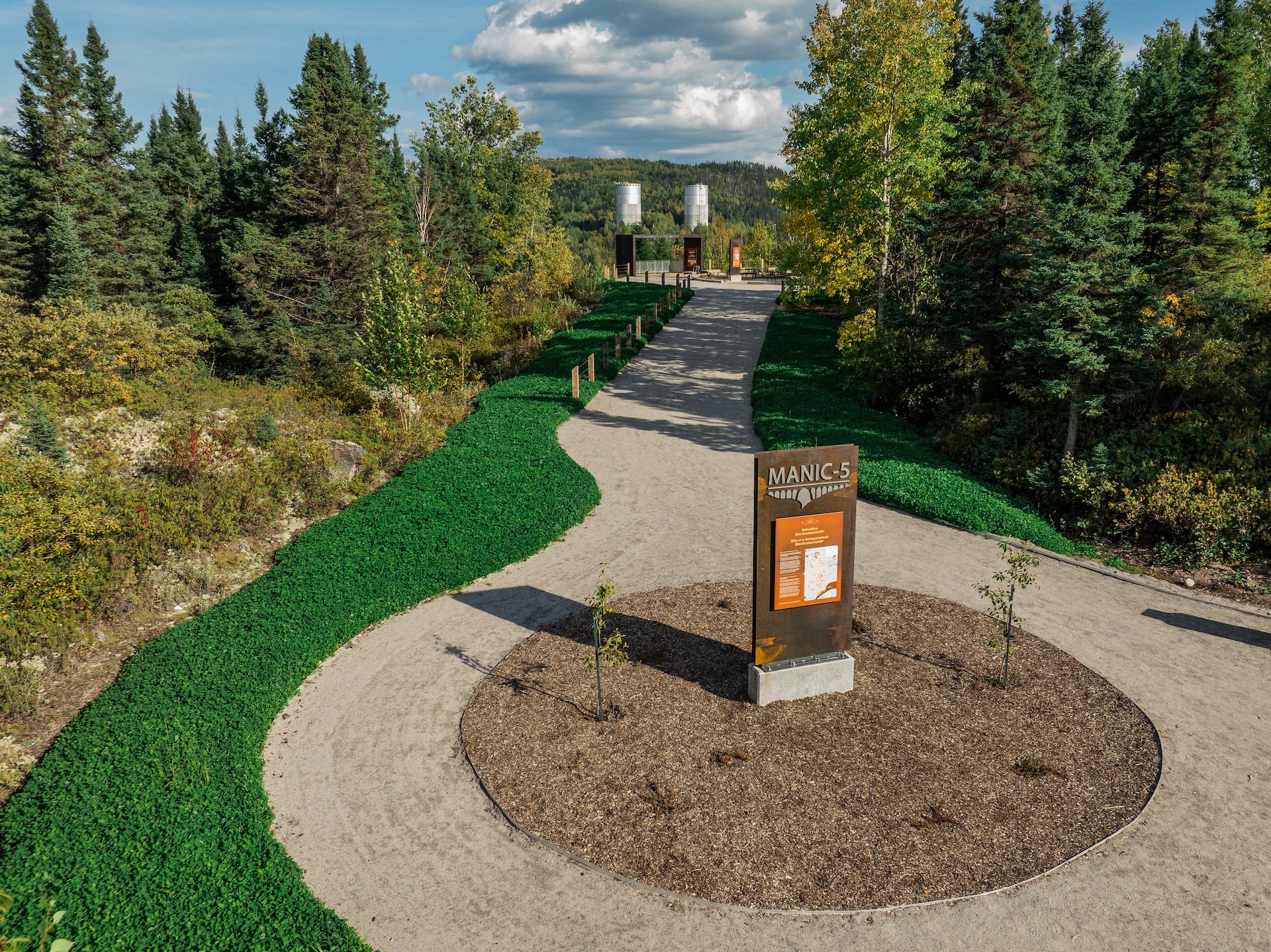 Sentier naturel menant à une installation de Studio Overall, avec panneau 