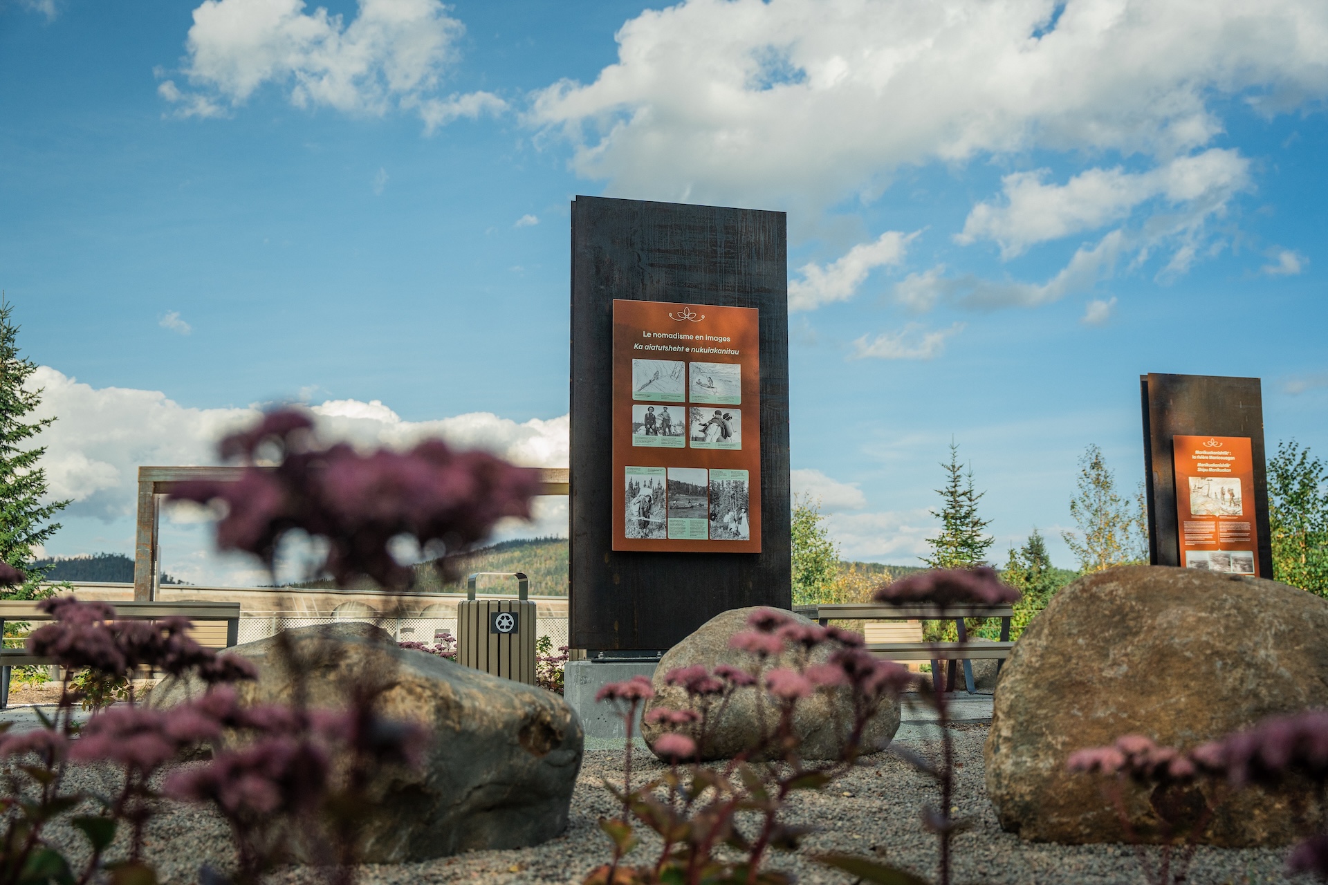 Installation muséographique extérieure avec panneaux d'information et rochers décoratifs.