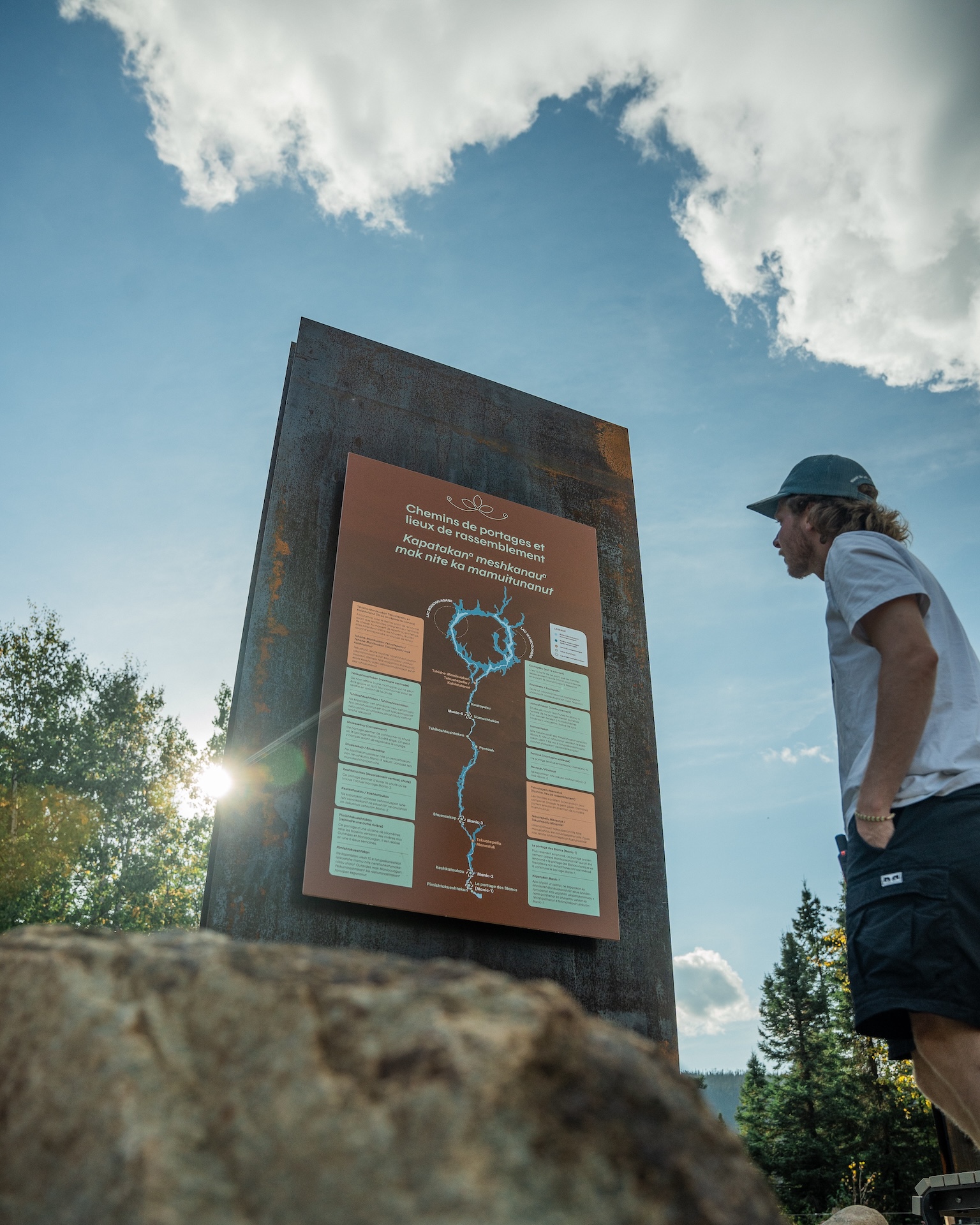 Panneau d'information sur les chemins de portages, observé par un visiteur en forêt.