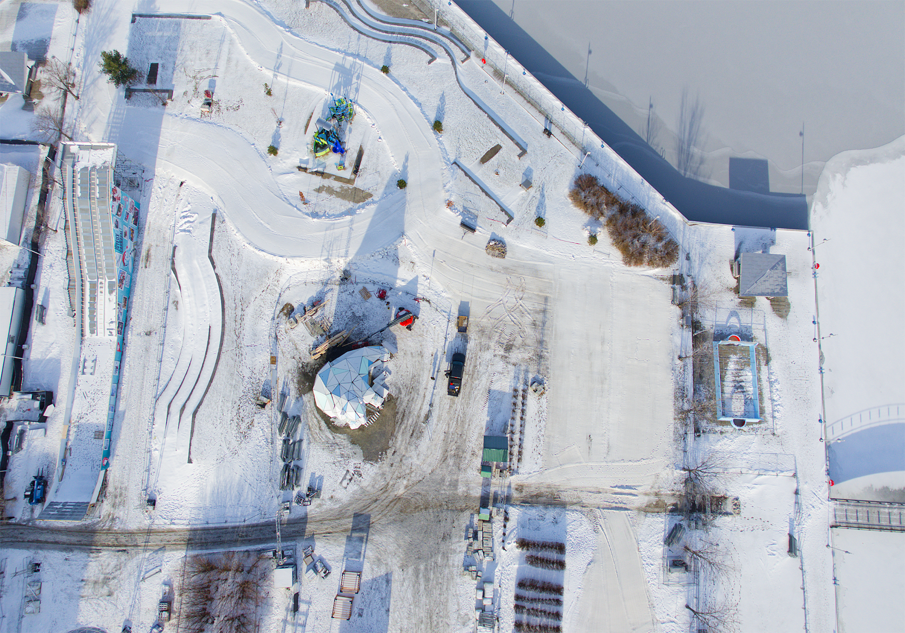 Vue aérienne d'une installation hivernale avec structures enneigées et équipements de construction.