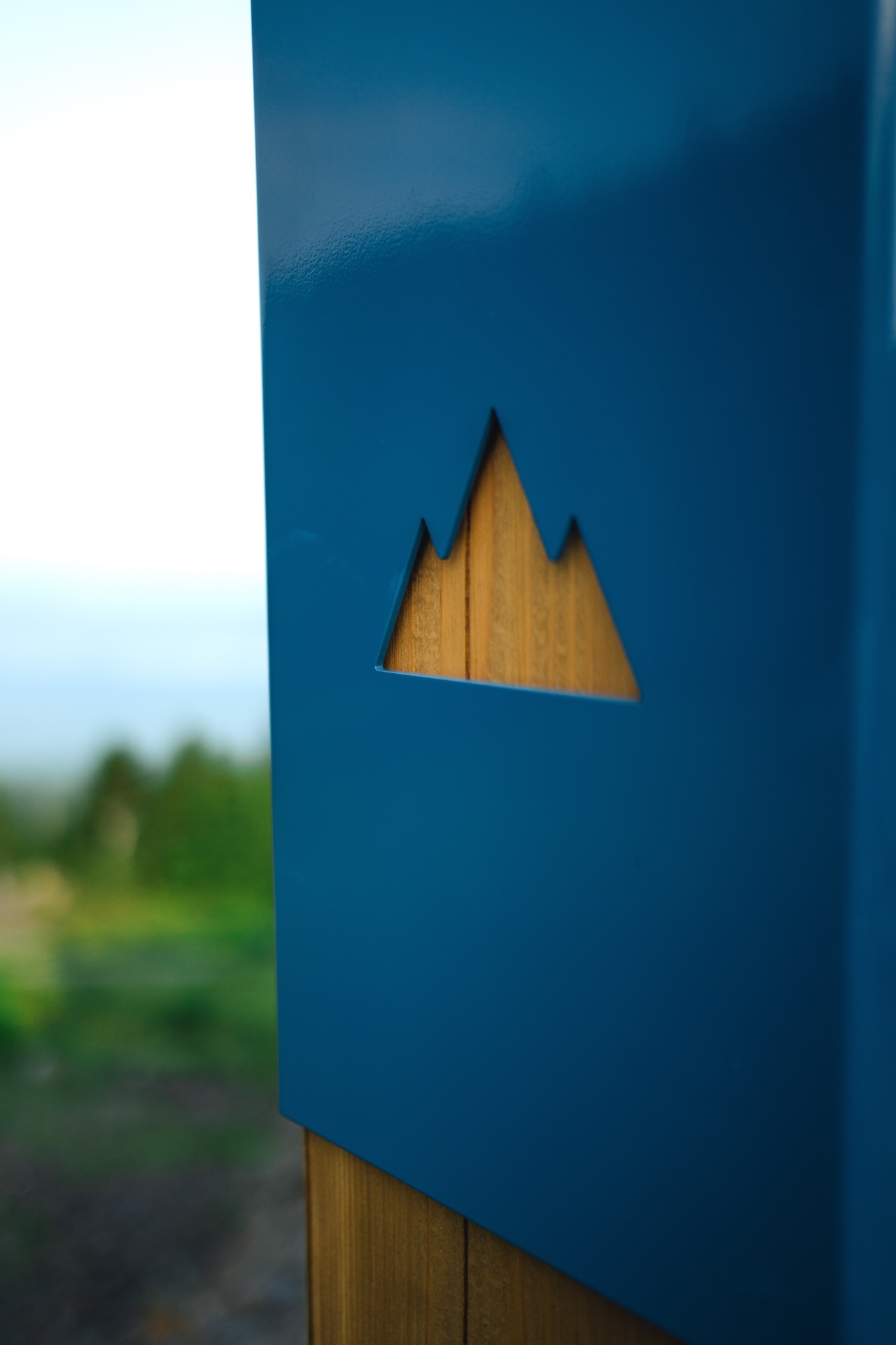 Logo de Studio Overall : montagne stylisée en bois sur fond bleu, symbole de design naturel et moderne.