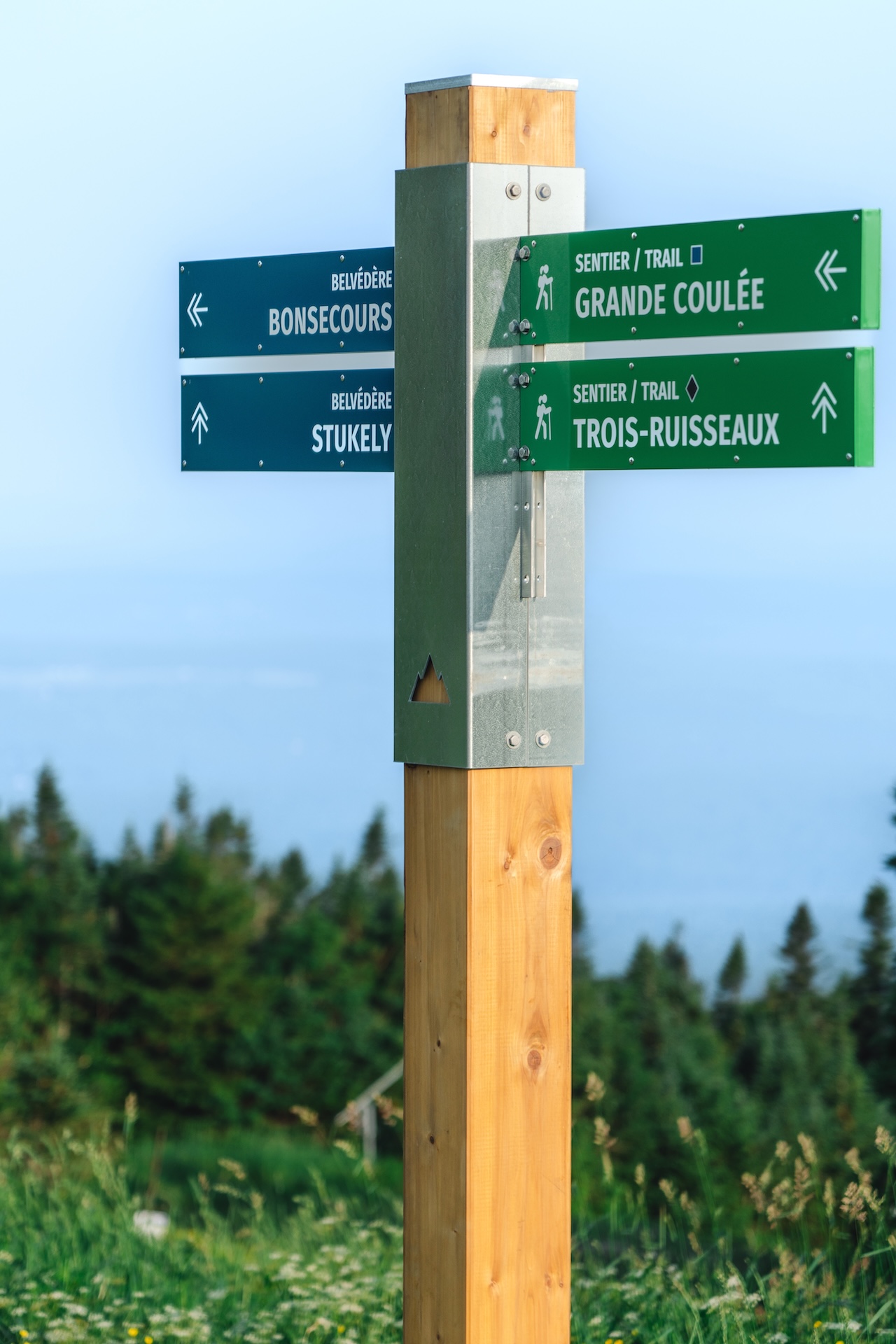 Panonceau de sentier en bois avec indications en français et symboles de randonnée.