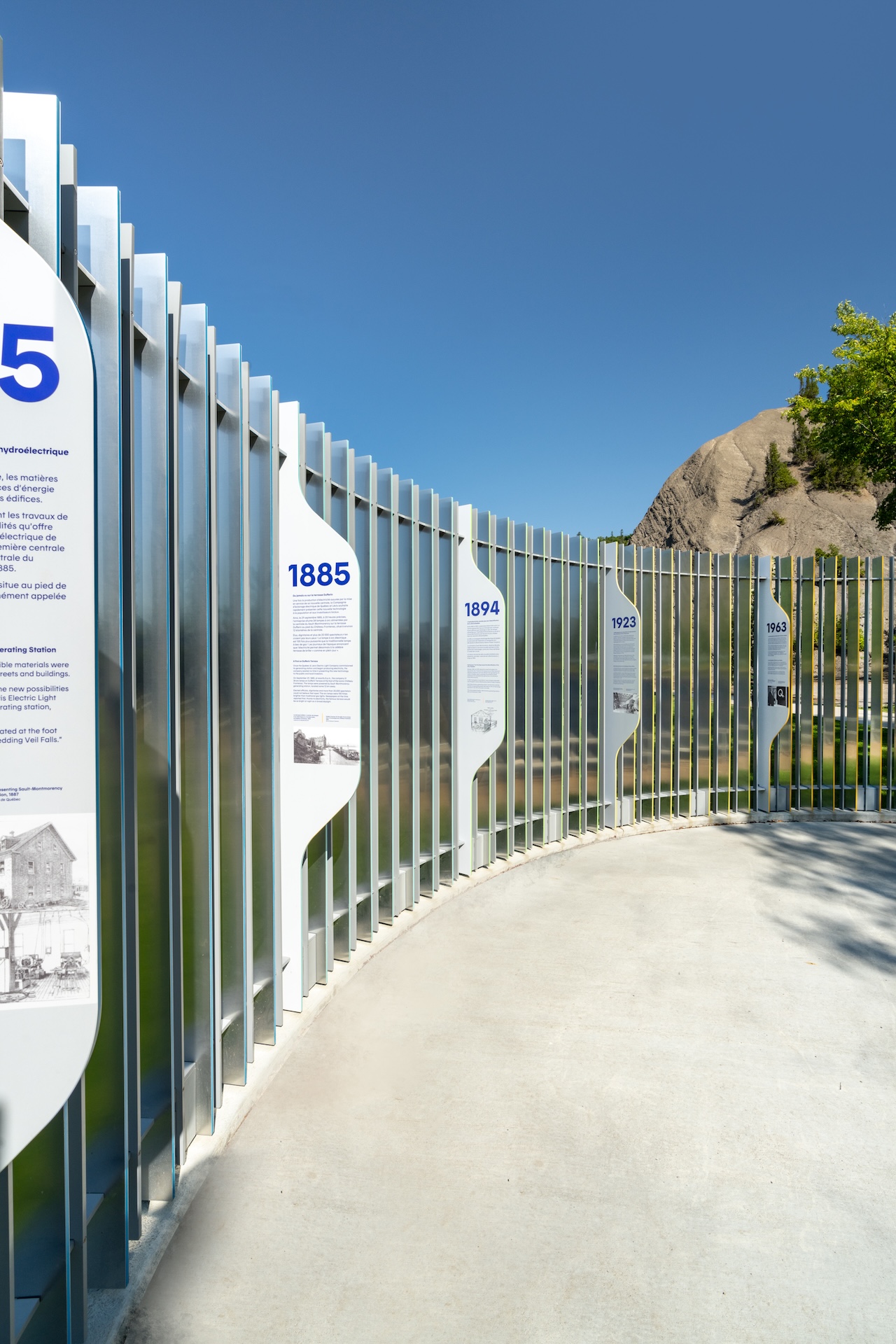 Installation muséographique moderne avec panneaux historiques en plein air.