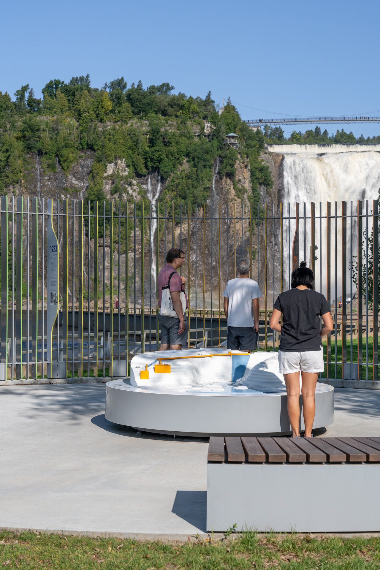 Visiteurs devant une installation muséographique près d'une cascade.