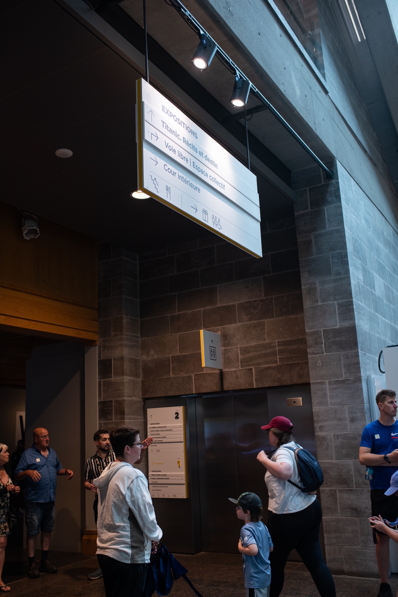 Visiteurs dans un espace muséal avec panneau d'exposition 