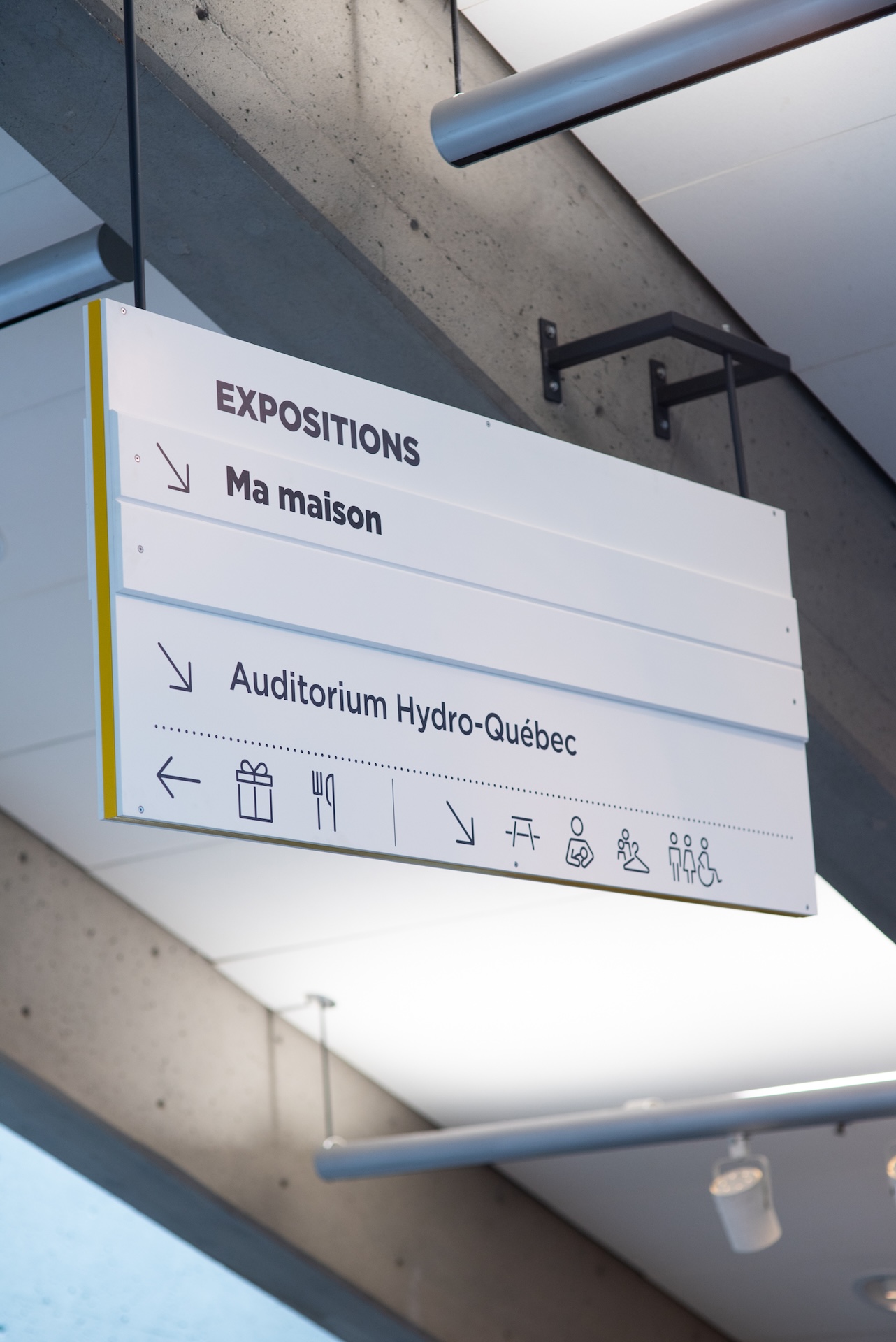 Signalétique muséale moderne indiquant les expositions, la salle Hydro-Québec et les services.