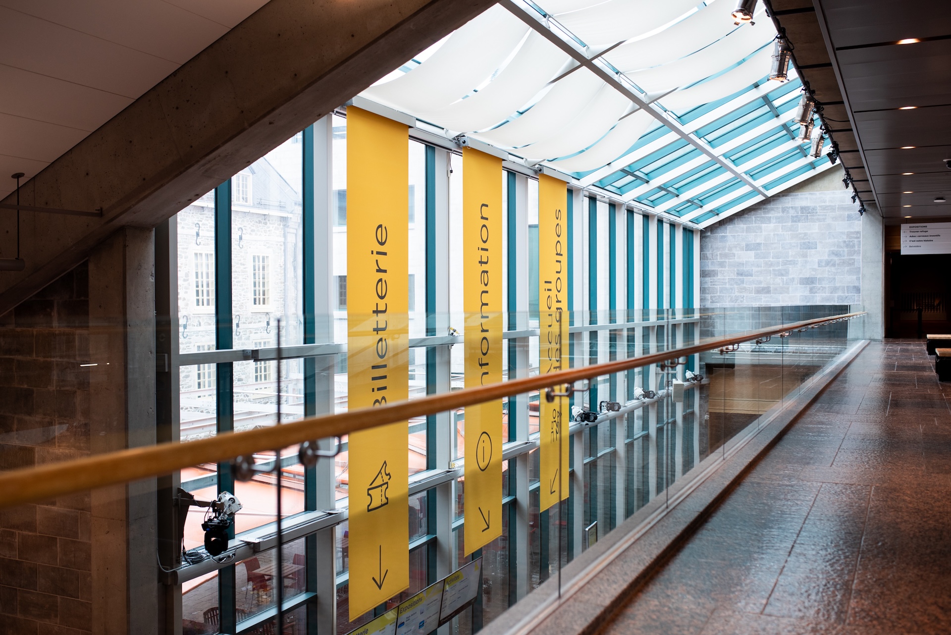 Hall lumineux avec panneaux jaunes indiquant billetterie, information et accueil des groupes.