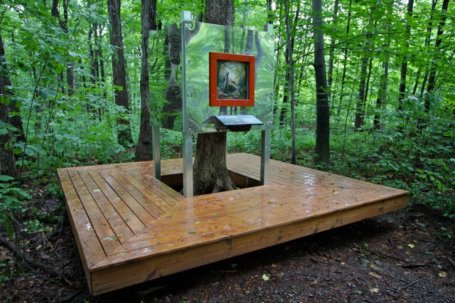 Installation forestière avec écran interactif et table en bois, œuvre de Studio Overall.