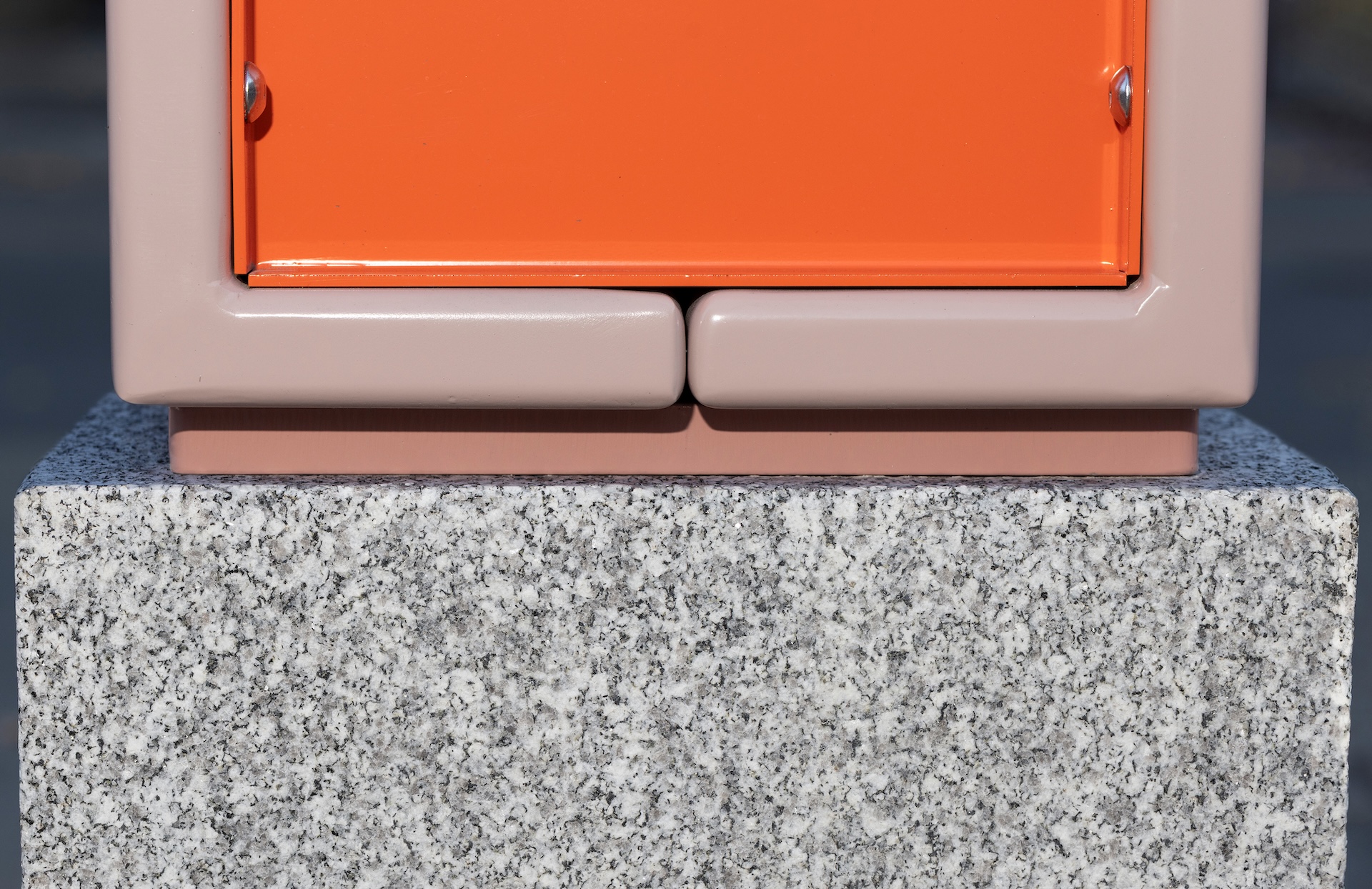 Installation design avec boîte orange sur socle en granite, œuvre de Studio Overall.