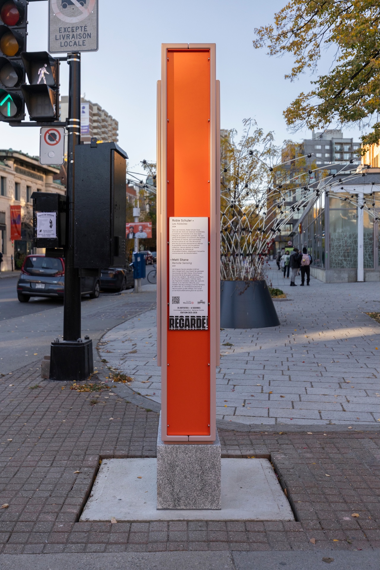 Installation artistique urbaine avec panneau orange, dans un quartier animé de Montréal.